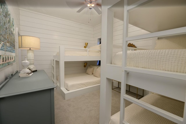 bedroom with ceiling fan, carpet floors, and wooden walls