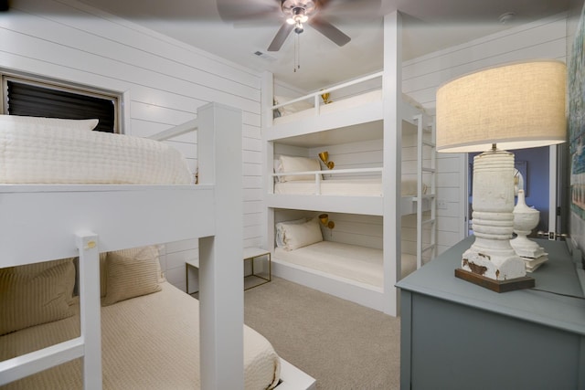 carpeted bedroom featuring ceiling fan and wood walls