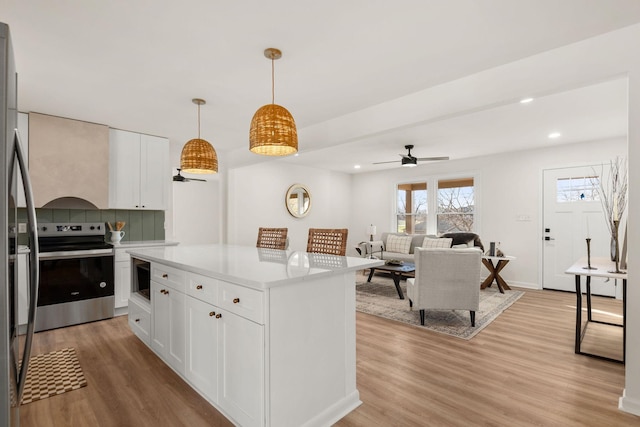 kitchen featuring tasteful backsplash, ceiling fan, stainless steel appliances, light hardwood / wood-style floors, and white cabinets