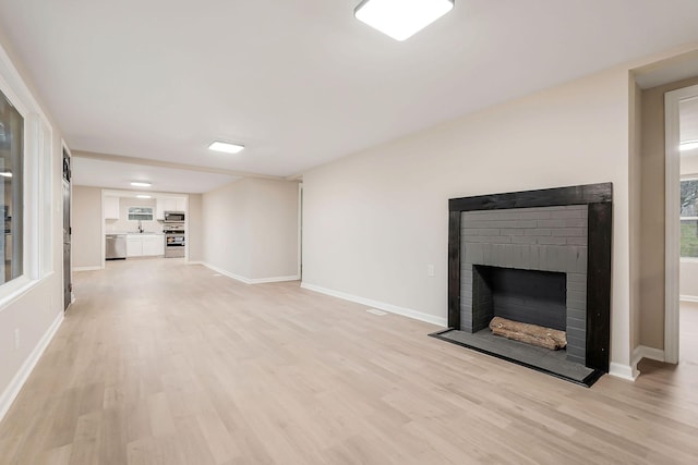 unfurnished living room with light hardwood / wood-style floors and a brick fireplace