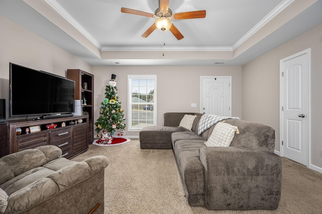 carpeted living room with a tray ceiling, ceiling fan, and ornamental molding