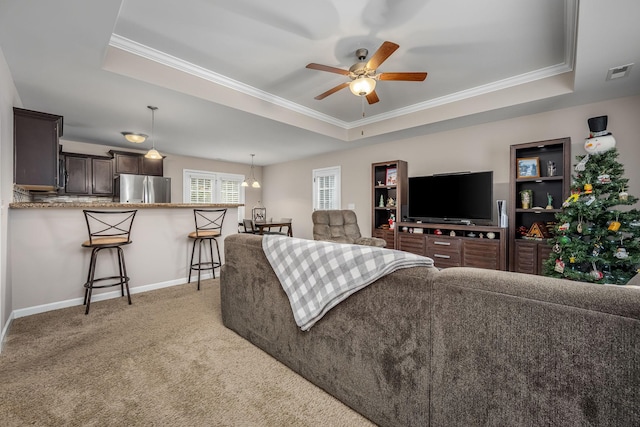 living room featuring ceiling fan, a raised ceiling, and crown molding