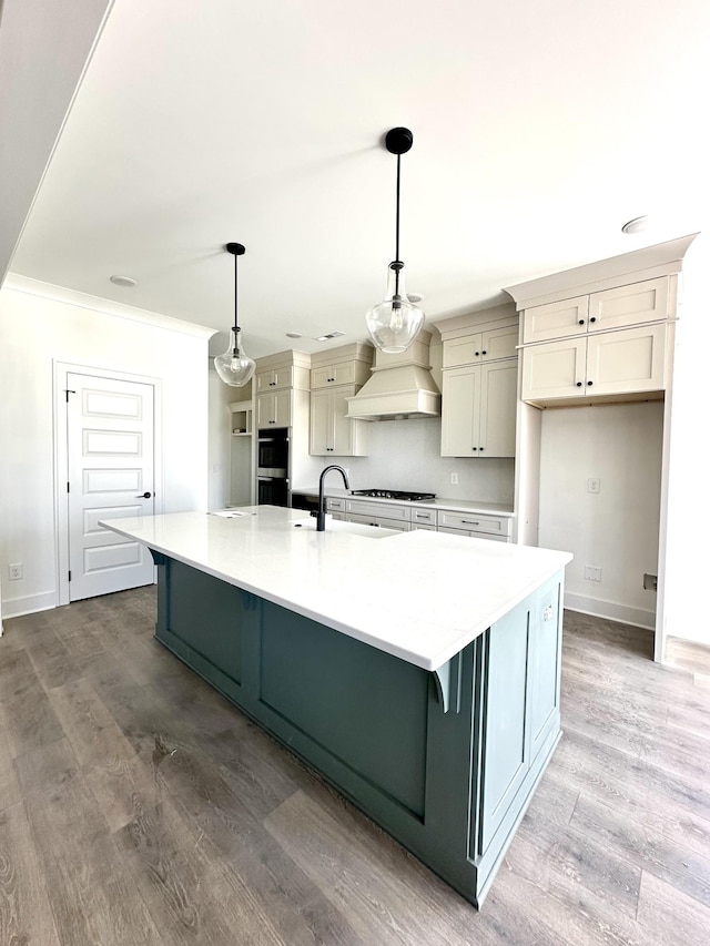 kitchen with a large island, custom exhaust hood, light wood-style flooring, and baseboards