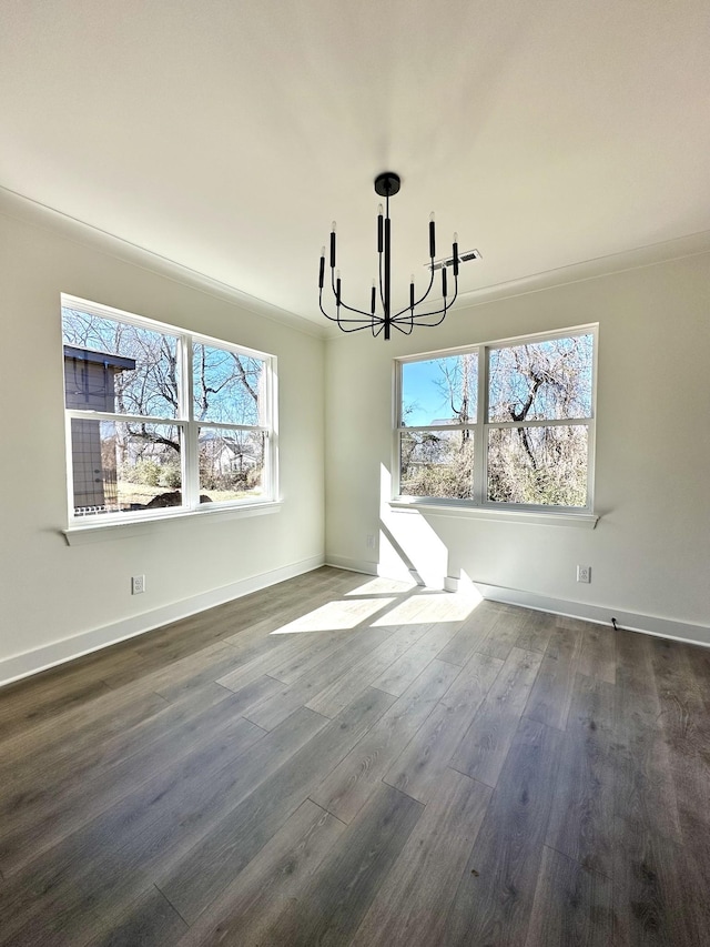 unfurnished dining area featuring baseboards, dark wood-type flooring, and an inviting chandelier