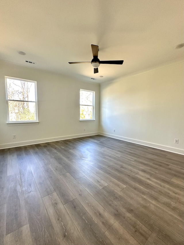 spare room featuring ceiling fan, dark wood-style flooring, visible vents, and baseboards