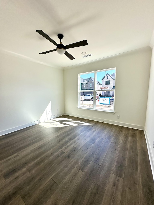 spare room featuring baseboards, dark wood-type flooring, visible vents, and a ceiling fan