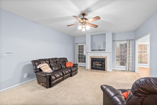 living room with ceiling fan, light colored carpet, and a tile fireplace