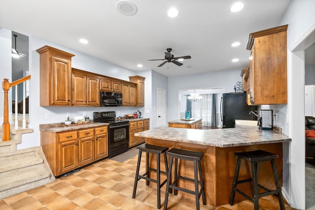 kitchen featuring black appliances, a kitchen bar, kitchen peninsula, light tile patterned flooring, and ceiling fan with notable chandelier