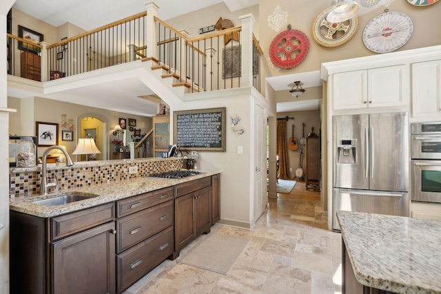 kitchen featuring backsplash, sink, a towering ceiling, dark brown cabinets, and stainless steel appliances