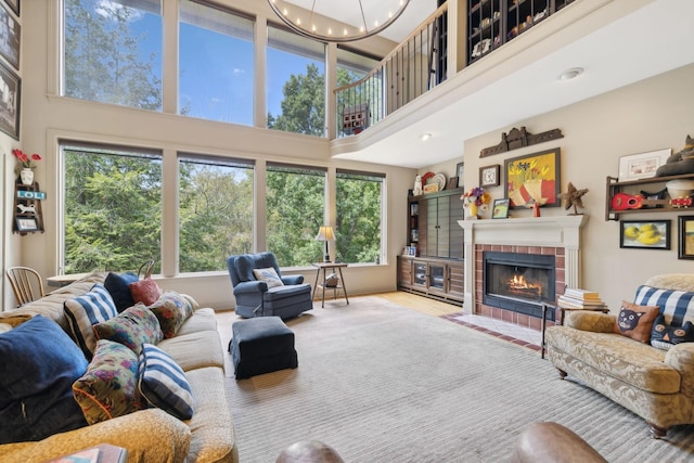 living room featuring a fireplace, a high ceiling, and an inviting chandelier