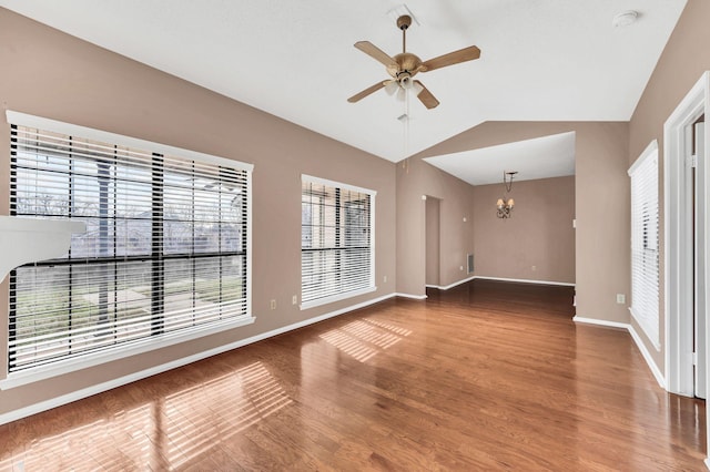 empty room featuring hardwood / wood-style flooring, ceiling fan with notable chandelier, and lofted ceiling