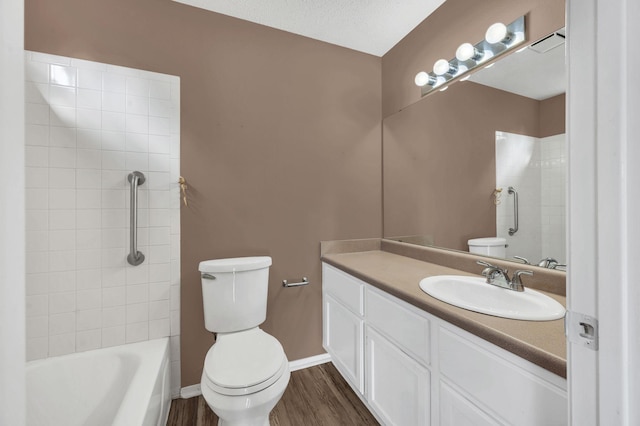 full bathroom with wood-type flooring, a textured ceiling, toilet, vanity, and tiled shower / bath