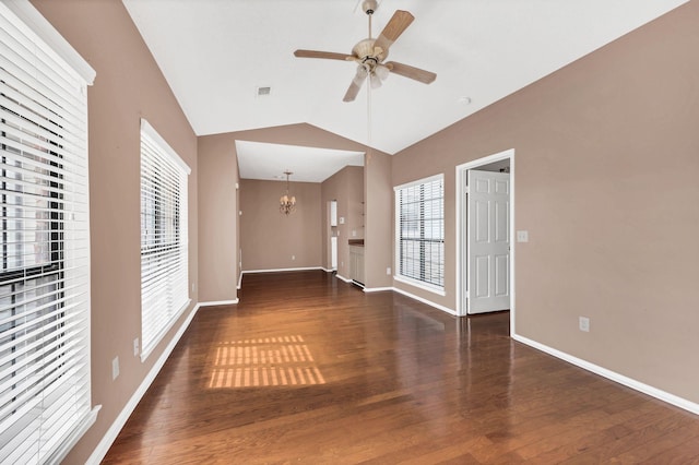 unfurnished living room with ceiling fan with notable chandelier, dark hardwood / wood-style flooring, and vaulted ceiling