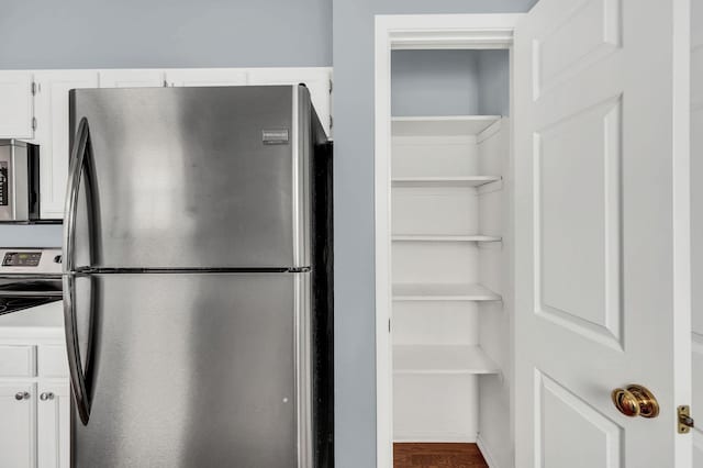 kitchen featuring hardwood / wood-style floors, stainless steel appliances, and white cabinetry