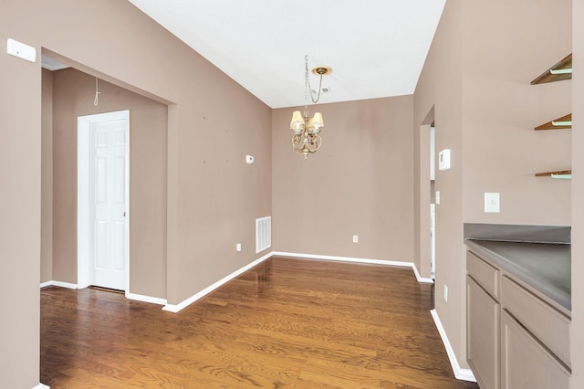 unfurnished dining area with a chandelier and dark hardwood / wood-style flooring