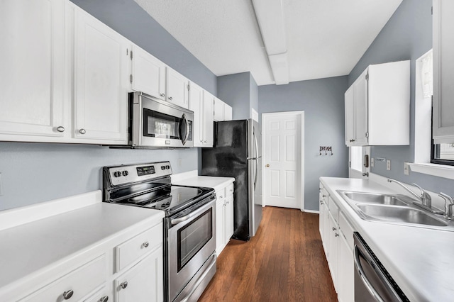 kitchen with stainless steel appliances, white cabinetry, dark wood-type flooring, and sink