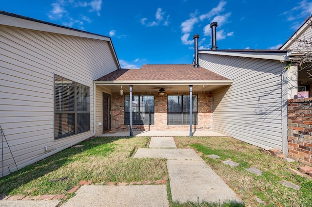 back of house with ceiling fan and a yard