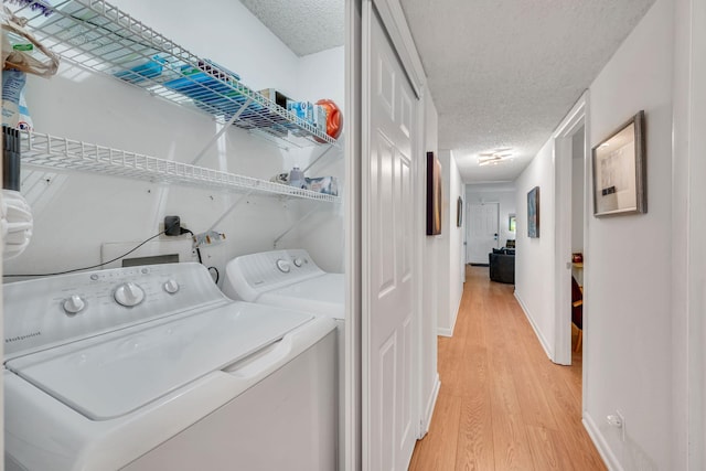 laundry area with wood-type flooring, washer and dryer, and a textured ceiling