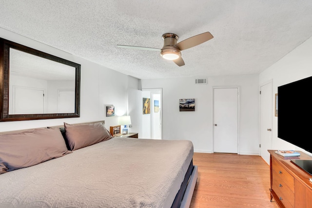 bedroom with light wood-type flooring, a textured ceiling, and ceiling fan