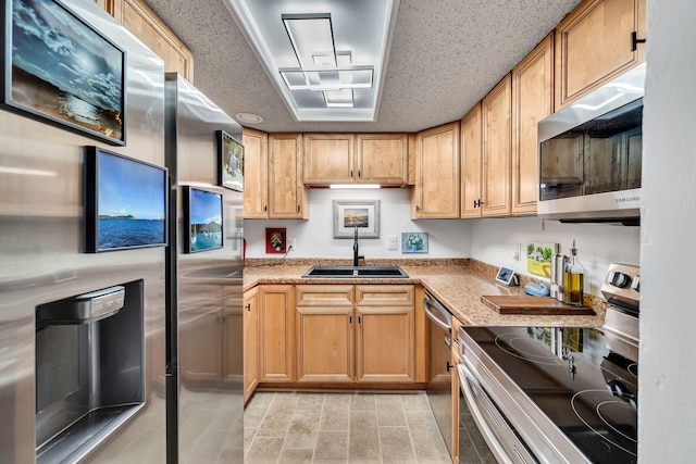 kitchen with stainless steel appliances, sink, and a textured ceiling