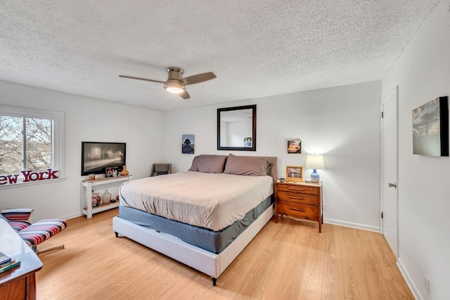 bedroom with ceiling fan, light hardwood / wood-style floors, and a textured ceiling