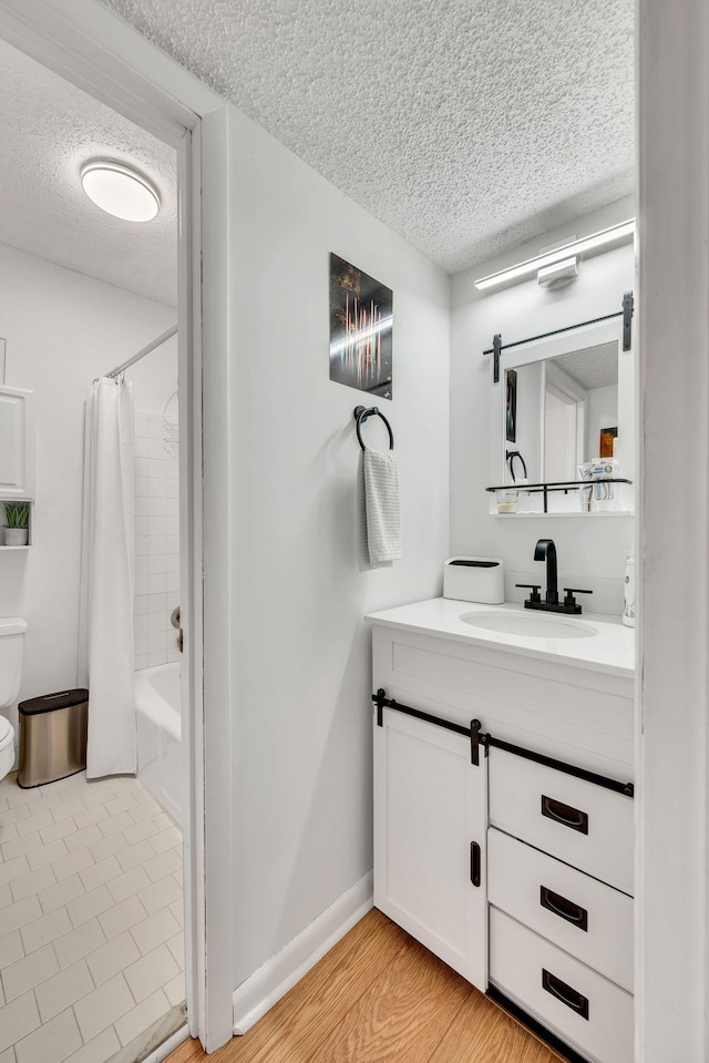 full bathroom with vanity, hardwood / wood-style floors, a textured ceiling, and shower / bath combo