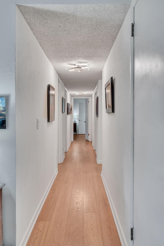 hall featuring a textured ceiling and light wood-type flooring