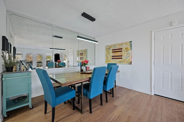 dining room featuring light hardwood / wood-style flooring, french doors, and a textured ceiling