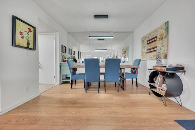 dining space featuring a textured ceiling and light wood-type flooring