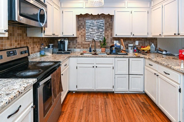 kitchen with white cabinetry, sink, wood-type flooring, and stainless steel appliances