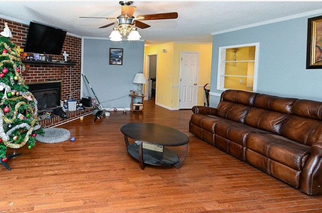 living room featuring hardwood / wood-style flooring, ornamental molding, ceiling fan, and a fireplace