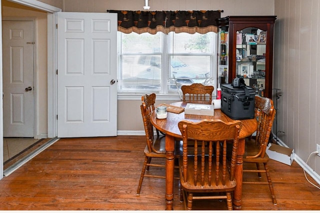 dining space with wood-type flooring and wooden walls