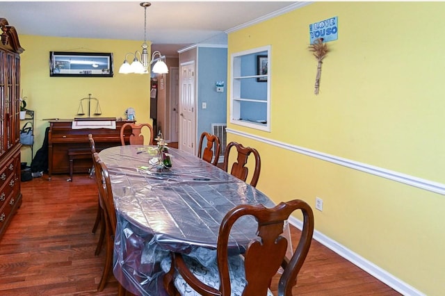 dining space featuring crown molding, dark hardwood / wood-style floors, and an inviting chandelier