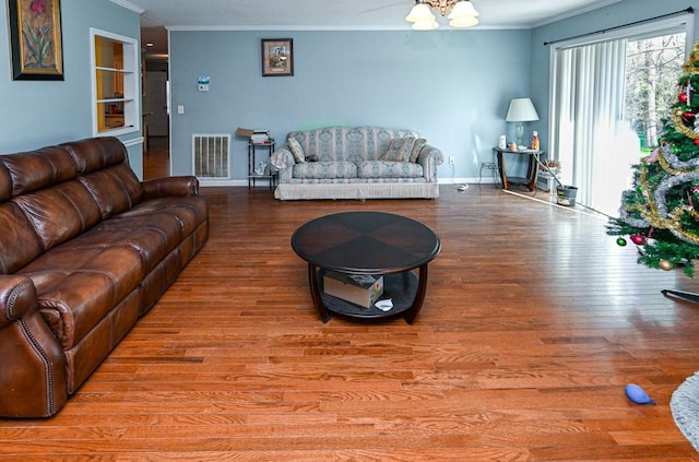 living room featuring crown molding, built in shelves, and light hardwood / wood-style flooring