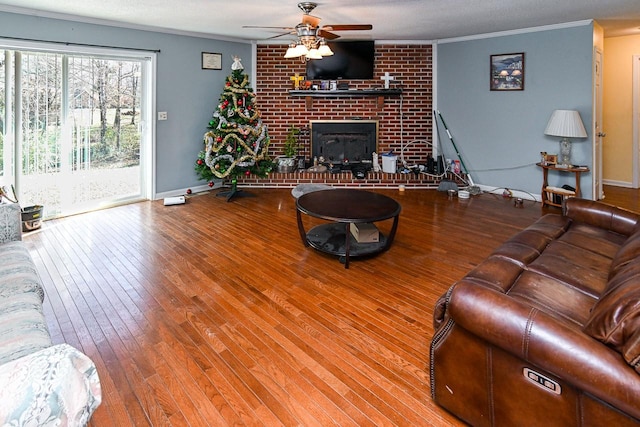 living room featuring hardwood / wood-style floors, a fireplace, ornamental molding, and ceiling fan