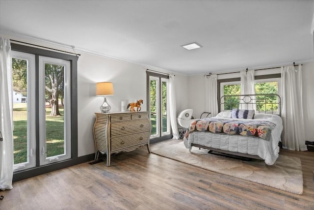 bedroom featuring hardwood / wood-style flooring, access to exterior, crown molding, and multiple windows