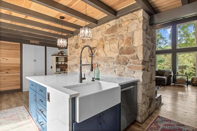 kitchen with blue cabinetry, decorative light fixtures, light stone countertops, and dark wood-type flooring