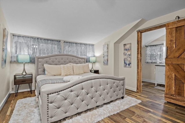 bedroom with a barn door and dark hardwood / wood-style floors