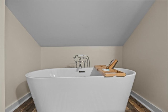 bathroom featuring a tub to relax in, hardwood / wood-style flooring, and lofted ceiling