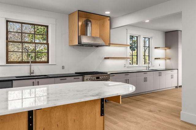 kitchen featuring white cabinets, wall chimney range hood, sink, plenty of natural light, and light hardwood / wood-style floors