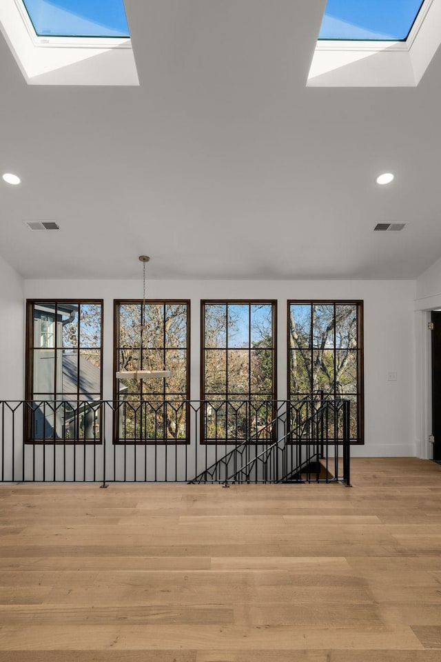 interior space featuring vaulted ceiling with skylight and light wood-type flooring