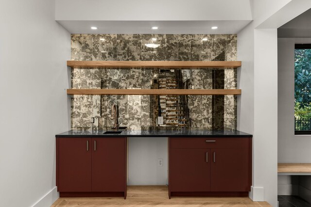 bar with light hardwood / wood-style flooring and sink