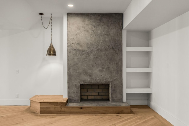 unfurnished living room featuring hardwood / wood-style flooring, built in shelves, and a fireplace