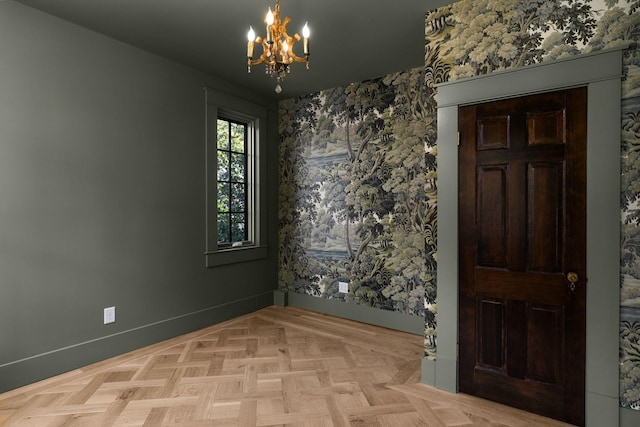 spare room with light parquet flooring and an inviting chandelier