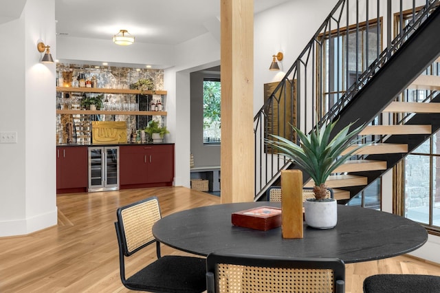 dining area with hardwood / wood-style floors, bar, and beverage cooler