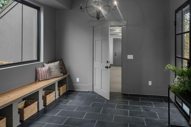 mudroom featuring dark tile patterned floors and a notable chandelier