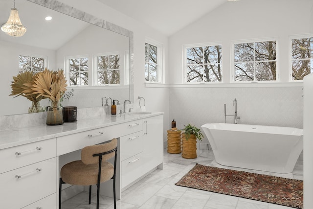 bathroom featuring lofted ceiling, vanity, and a tub