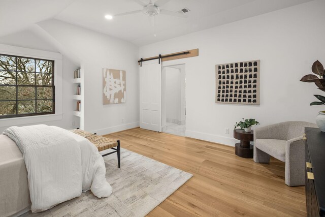 bedroom featuring a barn door, hardwood / wood-style floors, and ceiling fan