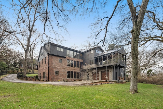 rear view of property featuring a garage, a yard, and a sunroom