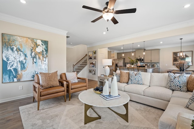 living room with ceiling fan with notable chandelier, light hardwood / wood-style floors, and ornamental molding